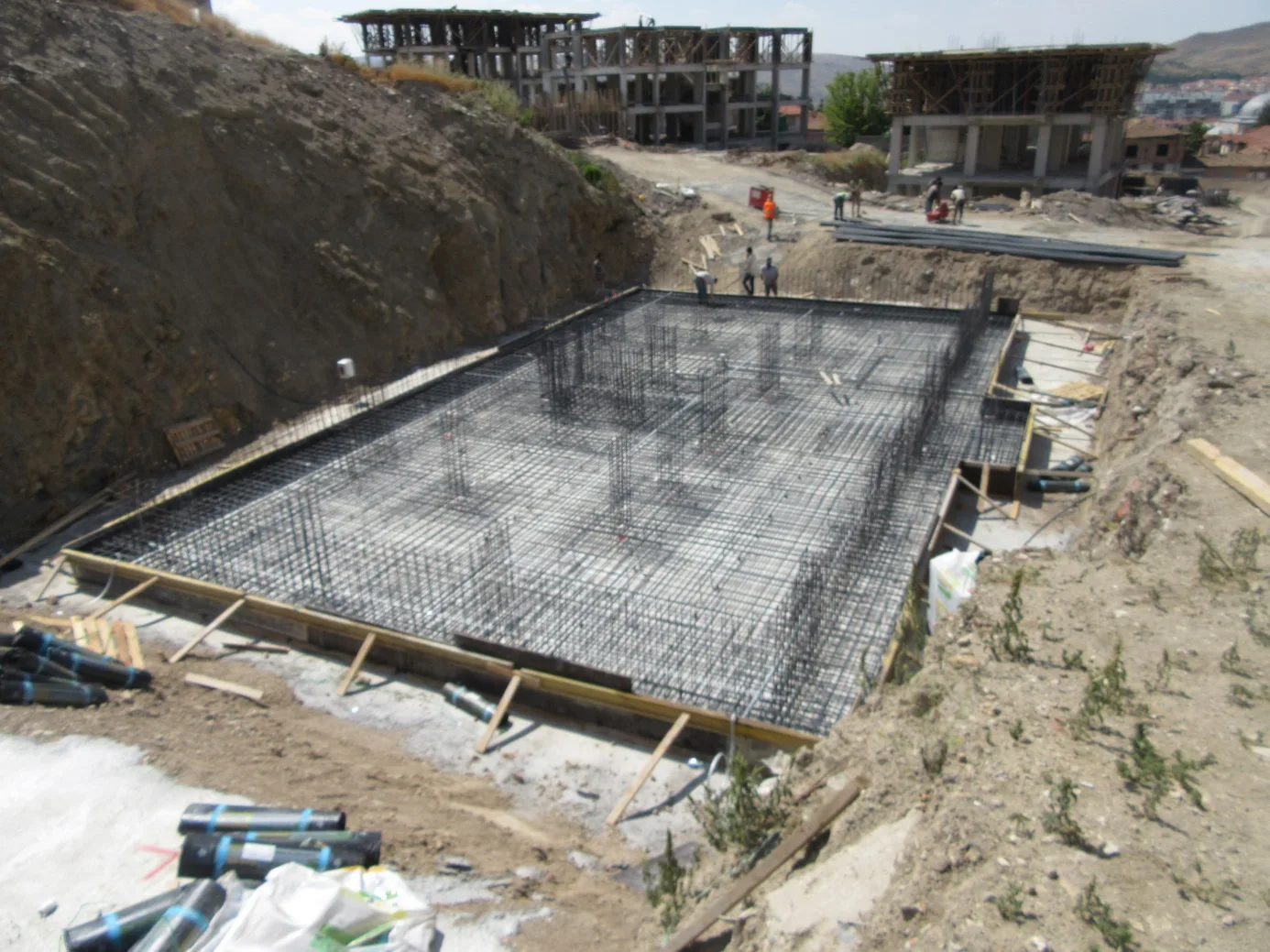 Sonrasında ise perde filizleri yerleştirilerek perde – kolon filiz donatılarının yerleştirilme işlemi tamamlanmıştır. Bu işlemler sırasında veya temel beton döküm işine geçilmeden temelde bulunan elektrik ve mekanik imalatları da yapılmıştır. Elektrik tesisatı olarak temel topraklama vs. gibi imalatlar, mekanik tesisatı olarak süzgeç vs. gibi giderlerin imalatları tamamlanmıştır. temel-perde-ve-kolon-filizleri-tamamlanmis